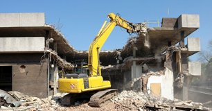 An excavator taking down a concrete building