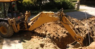 A backhoe digging a hole in a yard